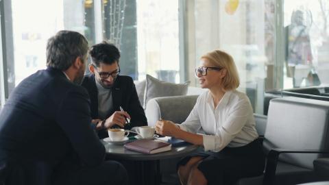Two men and a women sitting down to a meeting