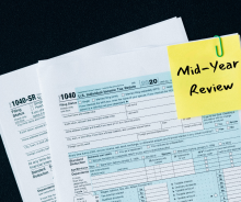 Tax forms with post-it that reads mid-year review